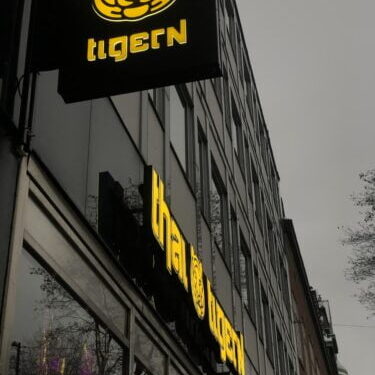 Fasad- och flaggskylt i gult till restaurang Thai tigern
